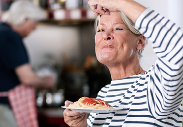 Rentnerin genießt Nudeln nach Einnahme von Kreon®